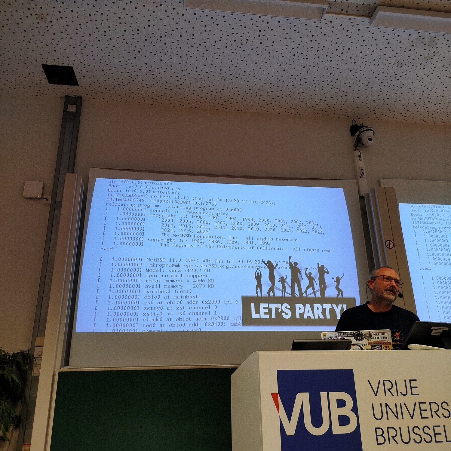 Walter presenting with a slide showing NetBSD 11.0 booting from NFS on Sun 2/120